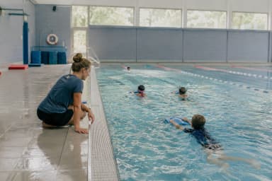 Trainerin am Beckenrand einer Schwimmschule